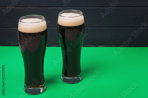 Photo Two glasses of stout beer on green colored table