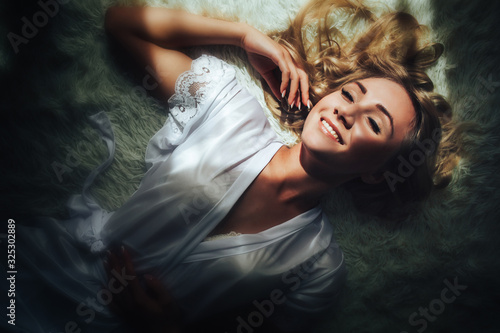 A beautiful girl is lying on a bed at dawn. Top view of the bride lying on the bed in a Bathrobe