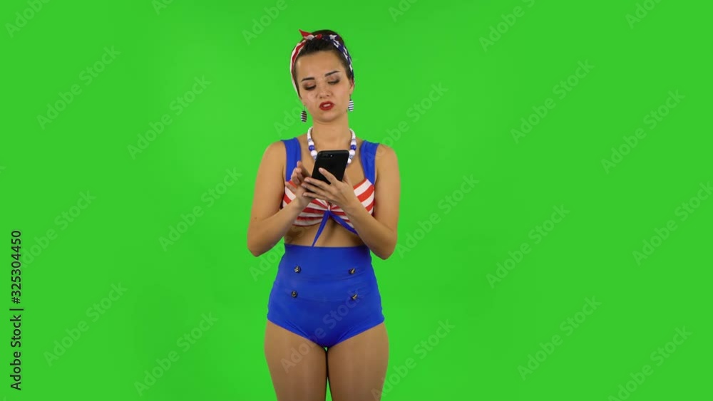 Beautiful girl in a swimsuit is angrily texting on her phone. Green screen Beautiful girl in a swimsuit is angrily texting on her phone. Green screen