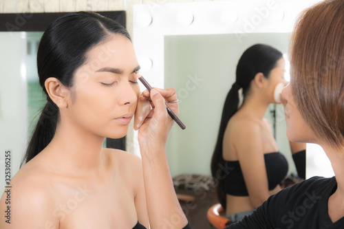 Woman applying makeup by makeup artist.