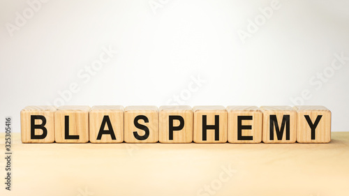 blasphemy word concept written on wooden cubes on a light table and a light white background