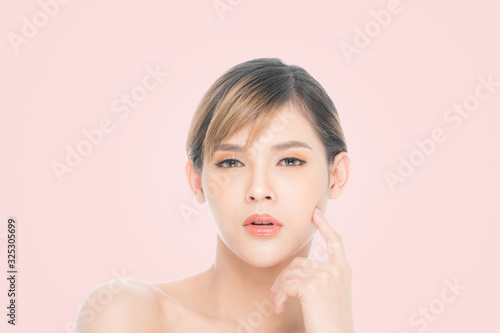 Beauty young woman with clean fresh skin, Proposing a product. Gestures for advertisement isolated on pink background, at copy space.