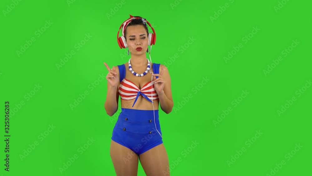 Beautiful girl in a swimsuit is dancing and enjoying music in big red headphones. Green screen Beautiful girl in a swimsuit is dancing and enjoying music in big red headphones. Green screen