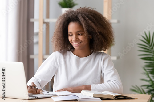 Happy african american teen high school student studying with laptop