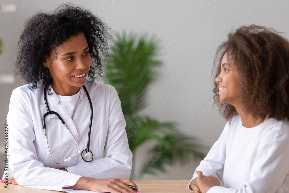 Friendly african american female doctor talking to teen girl patient Friendly african american female doctor talking to teen girl patient