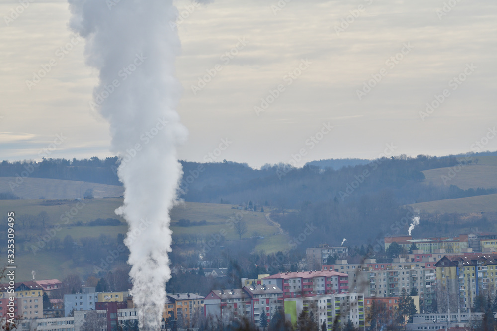 White smoke comes from the chimney of a power plant to produce heat in winter for houses and apartment buildings