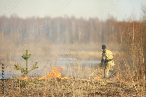 firefighter puts out grass / forest fire, dry grass burns, wind blows