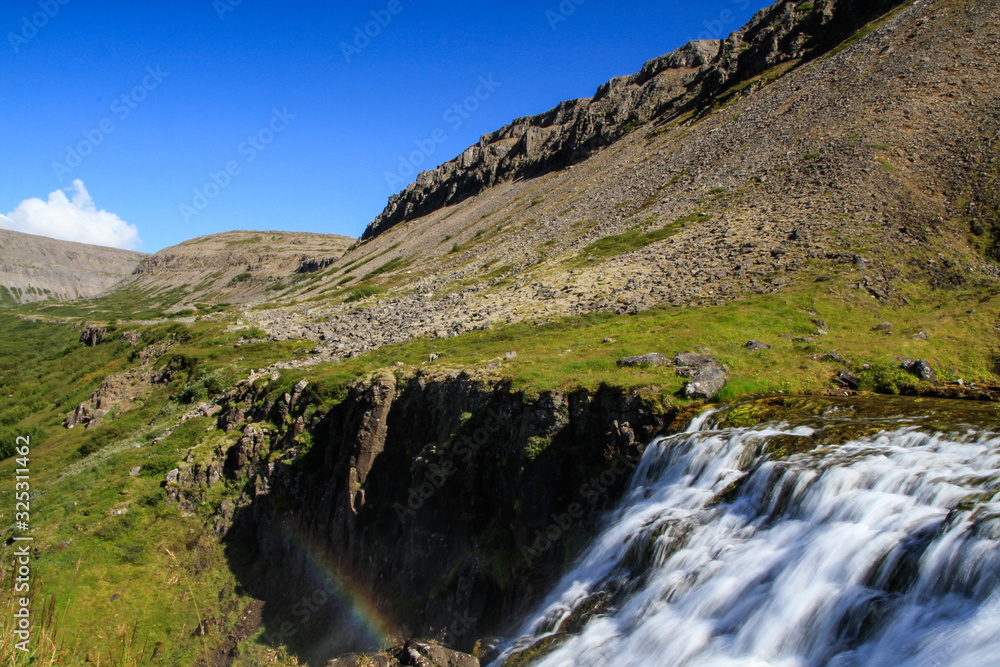 Der Dynjandi Wasserfall, einer der schönsten Wasserfälle Islands im Norden der Insel in den Westfjorden, vor blauem Himmel