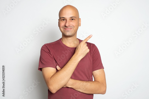 Happy smiling bald man is pointing finger. Isolated photo