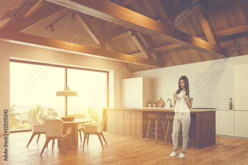 Woman in attic kitchen with bar and table photo