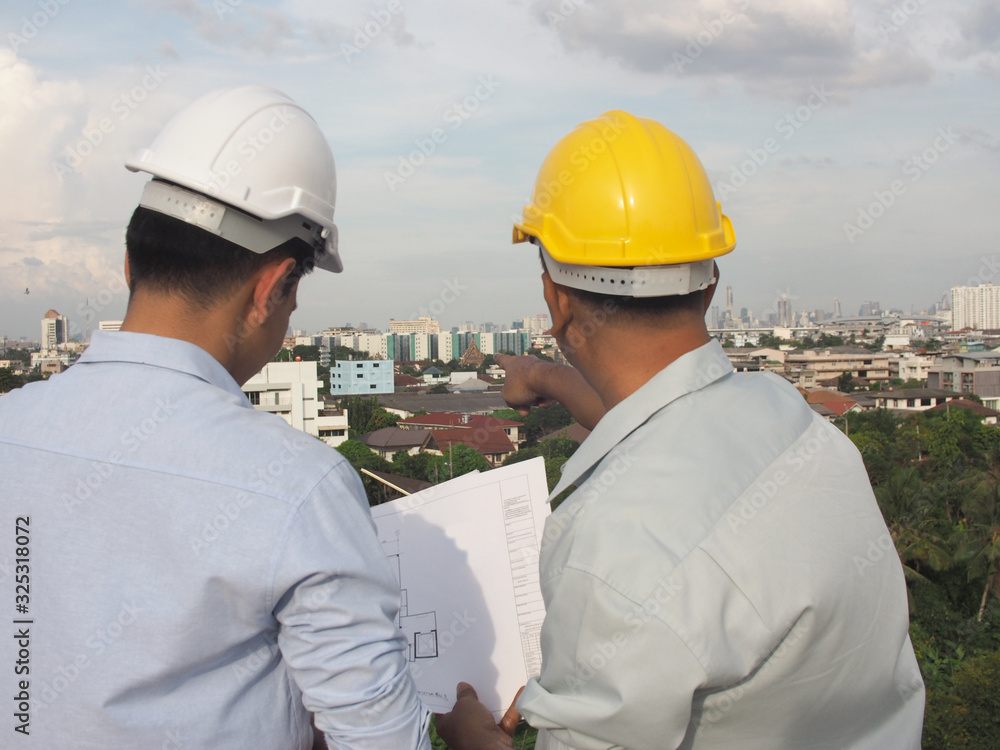 asian male engineer or foreman and male architects Asian people discussing blueprint of future building or check documents and business workflow. asian male engineer or foreman and male architects Asian people discussing blueprint of future building or check documents and business workflow.