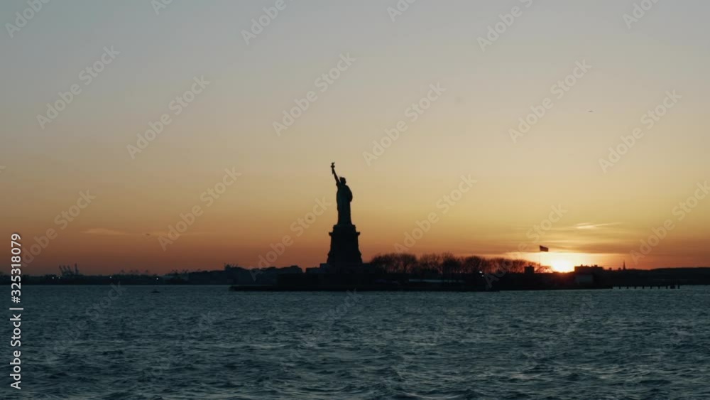 The Statue of Liberty filmed from the Hudson River with its silhouette cropped behind an incredible sunset. The Statue of Liberty filmed from the Hudson River with its silhouette cropped behind an incredible sunset.