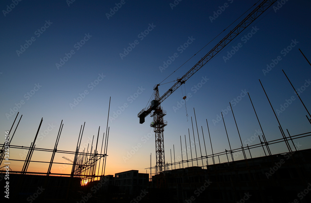 Cranes at work, silhouetted on construction sites