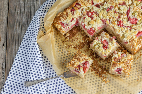 strawberry rhubarb crumble cake on blue brindle plate on a baking paper
