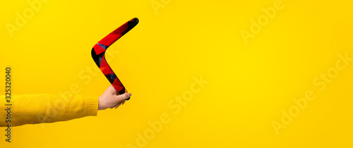 boomerang in female hand over yellow background, panoramic mock-up with space for text photo