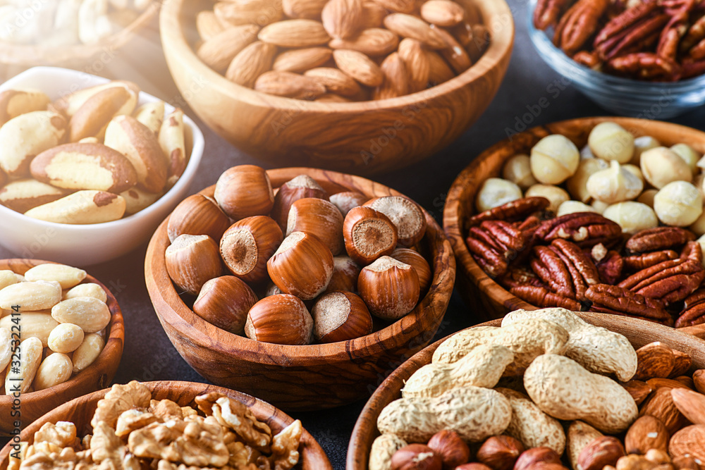 Mix nuts in wooden bowls on dark stone table. Almonds, pistachio, walnuts, cashew, hazelnut. Mix nuts in wooden bowls on dark stone table. Almonds, pistachio, walnuts, cashew, hazelnut.