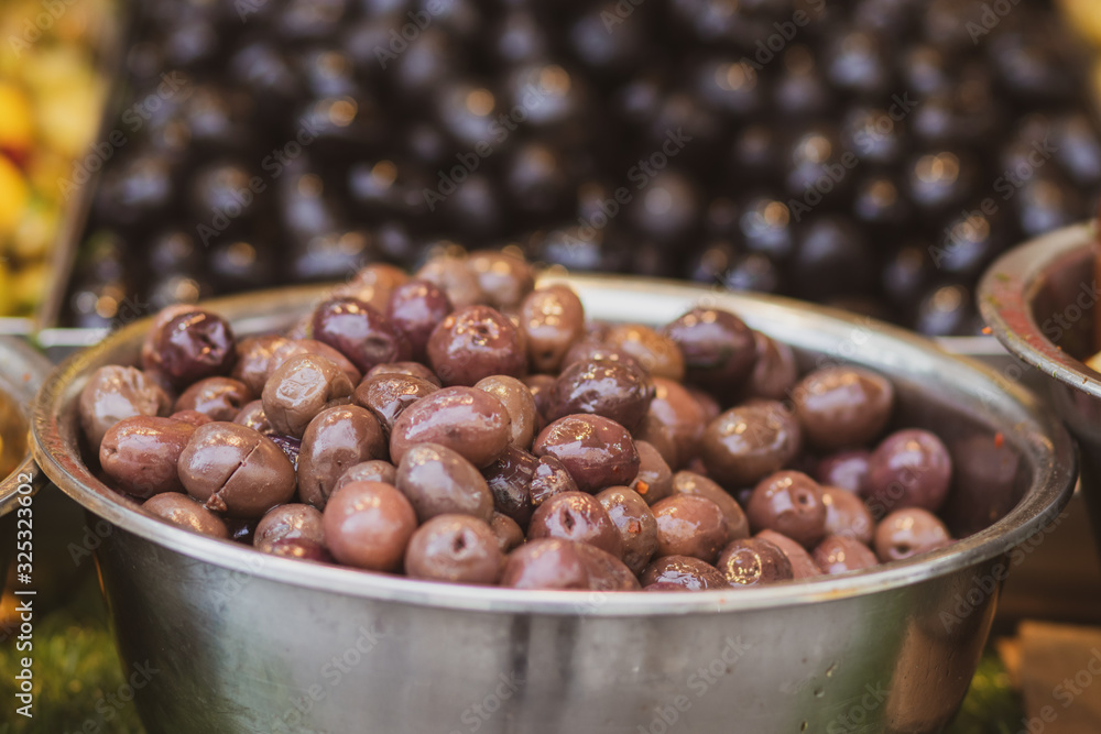 Obraz premium A pile of shiny Syrian brown olives and full of oil. Inside a metal bowl. Arabic style. The Old Market of Mahane Yehuda, Jerusalem.