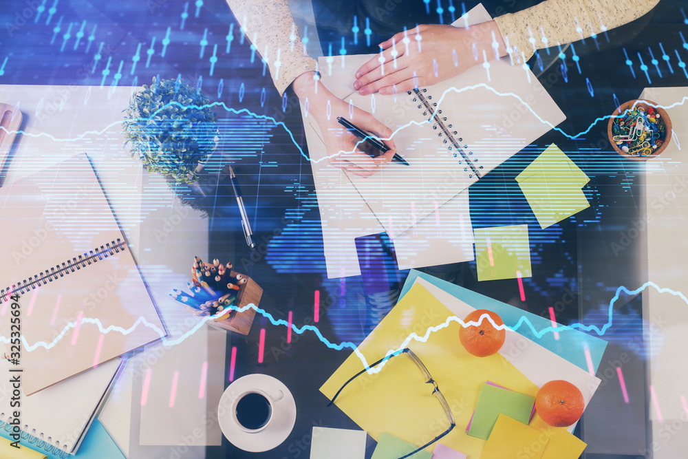 Hand taking notes in notepad. Forex chart holograms in front. Concept of research. Double exposure Hand taking notes in notepad. Forex chart holograms in front. Concept of research. Double exposure