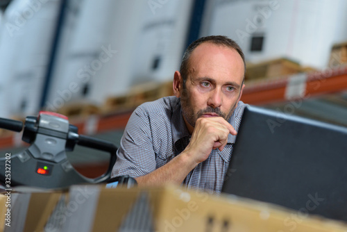 business man posing typing on his computer in a warehouse