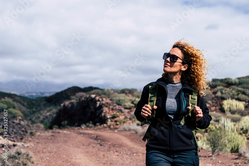 Happy independent beautiful adult caucasian woman in trekking outdoor leisure activity enjoying the nature - modern active people walking with backpack at the mountain photo