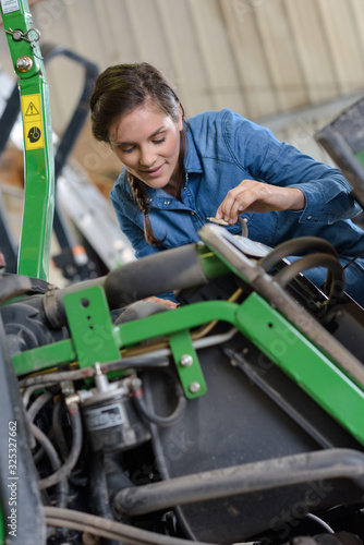 female agricultural mechanic checking tractor