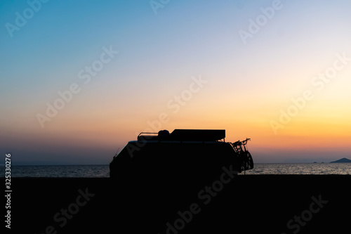 Motorhome silhouette on the beach in the sunset Beautiful orange sky color and calm sea in the background. Camper van lifestyle