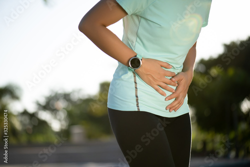 Sport girl have stomach pain after jogging work out in park. Healthcare and Sport concept.