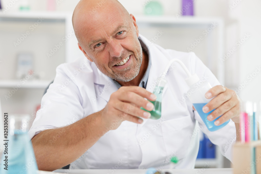 mature lab worker conducting a chemical experiment mature lab worker conducting a chemical experiment