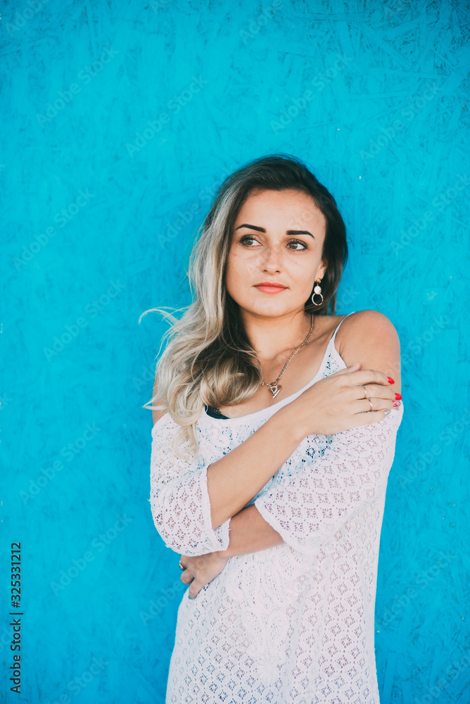 Beautiful girl in a white light dress on a blue wooden background Beautiful girl in a white light dress on a blue wooden background