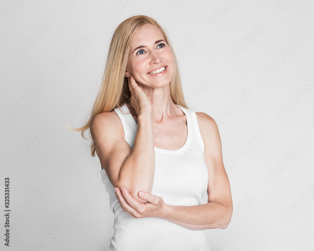 Fototapeta premium Portrait of middle aged woman looking up at grey studio