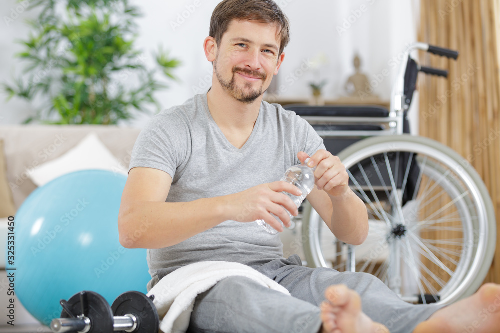young handsome disabled man drinking water after rehabilitation sport