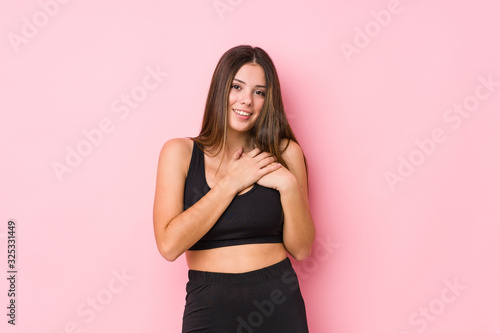 Young fitness caucasian woman isolated has friendly expression, pressing palm to chest. Love concept. © Asier