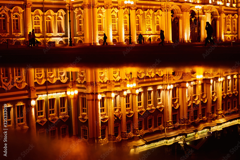 Silhouette of people with reflection in the puddle at Dvortsovaya square in Saint Petersburg at night