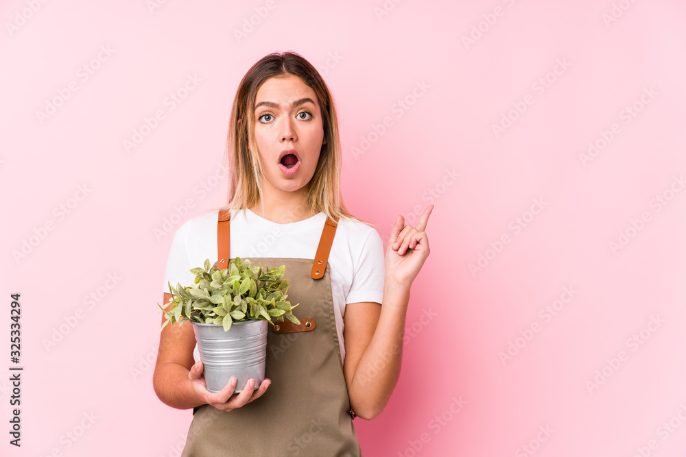 Young caucasian gardener woman in a pink background pointing to the side Young caucasian gardener woman in a pink background pointing to the side