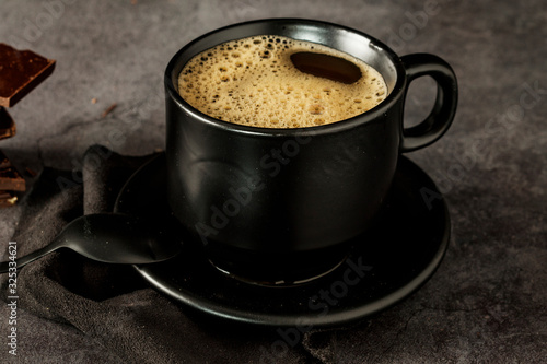 Black coffee cup with coffee on a dark background. With copy space for your text. Cup of coffee on a black background low key copy space.
