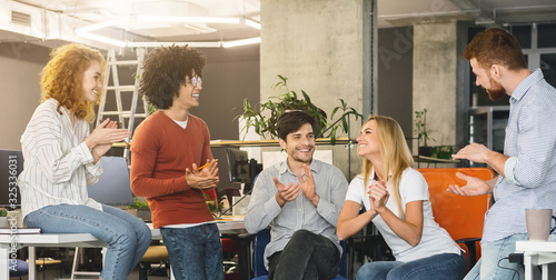 Young creative team cheering new comer girl in office