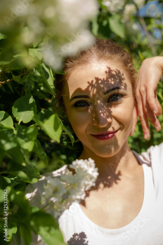 Beautiful girl is walking in the spring park near the trees in bloom. Spring season, sunny weather. photo