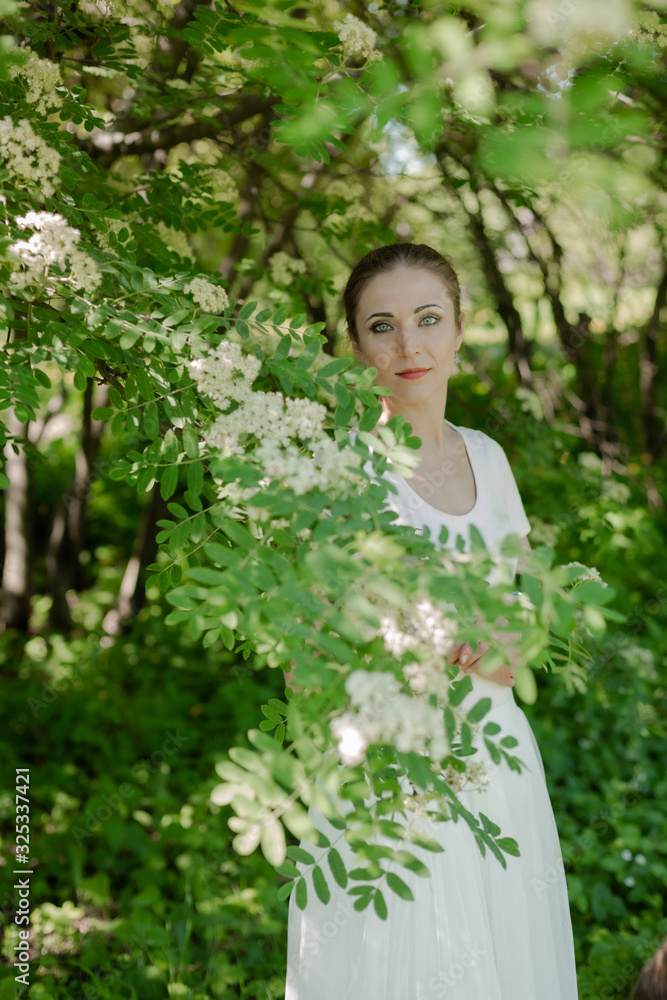 Beautiful girl is walking in the spring park near the trees in bloom. Spring season, sunny weather. Beautiful girl is walking in the spring park near the trees in bloom. Spring season, sunny weather.