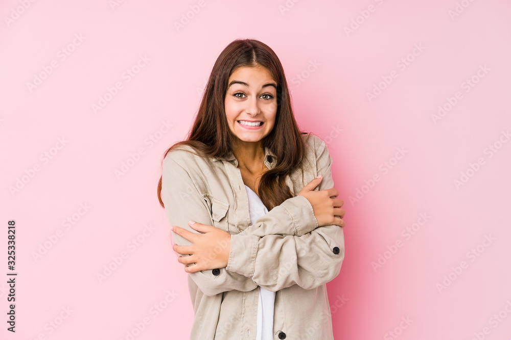 Young caucasian woman posing in a pink background going cold due to low temperature or a sickness. Young caucasian woman posing in a pink background going cold due to low temperature or a sickness.