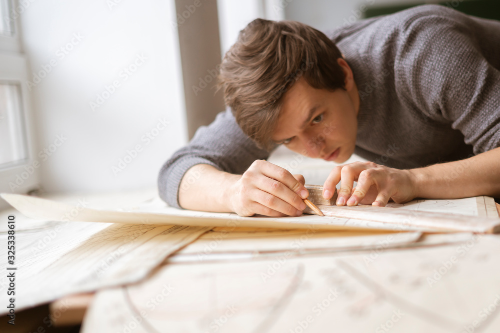 caucasian young architect doing drawings at the workplace, making the sketch or draft of new building caucasian young architect doing drawings at the workplace, making the sketch or draft of new building