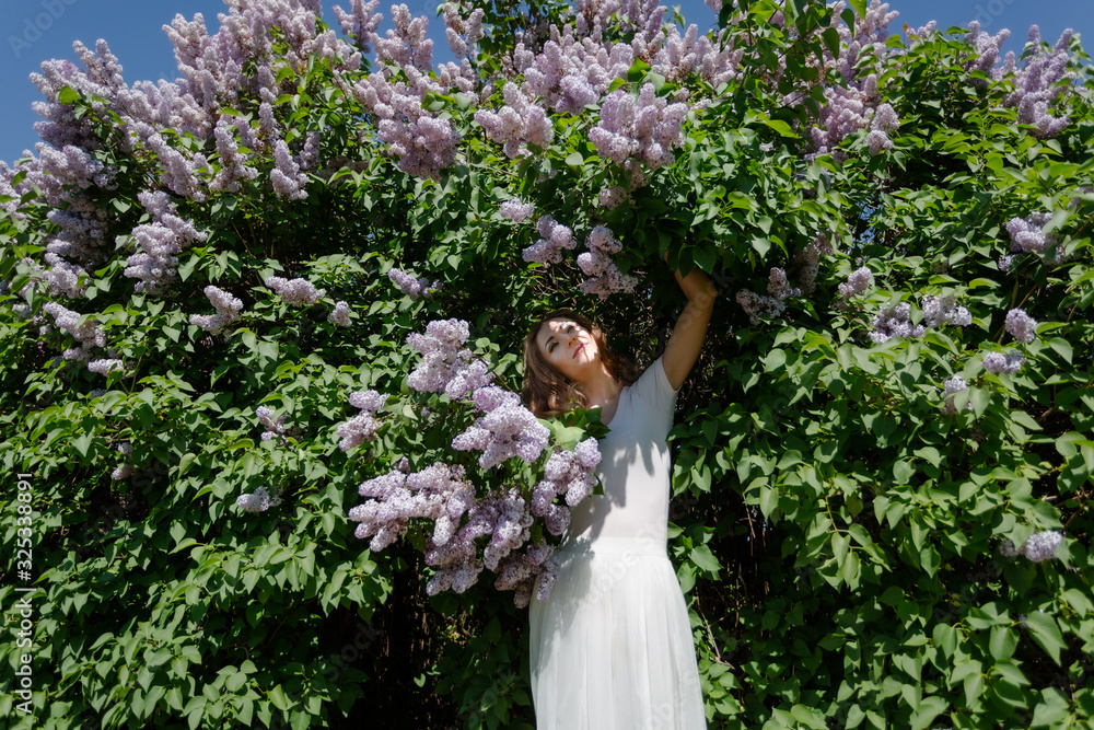 Red hair woman is near the lilac tree in blossom. Spring time, sunny weather. Red hair woman is near the lilac tree in blossom. Spring time, sunny weather.