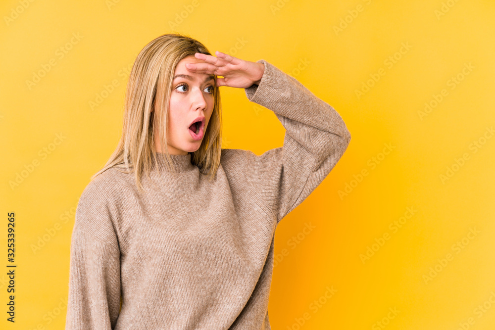 Young blonde caucasian woman isolated looking far away keeping hand on forehead. Young blonde caucasian woman isolated looking far away keeping hand on forehead.