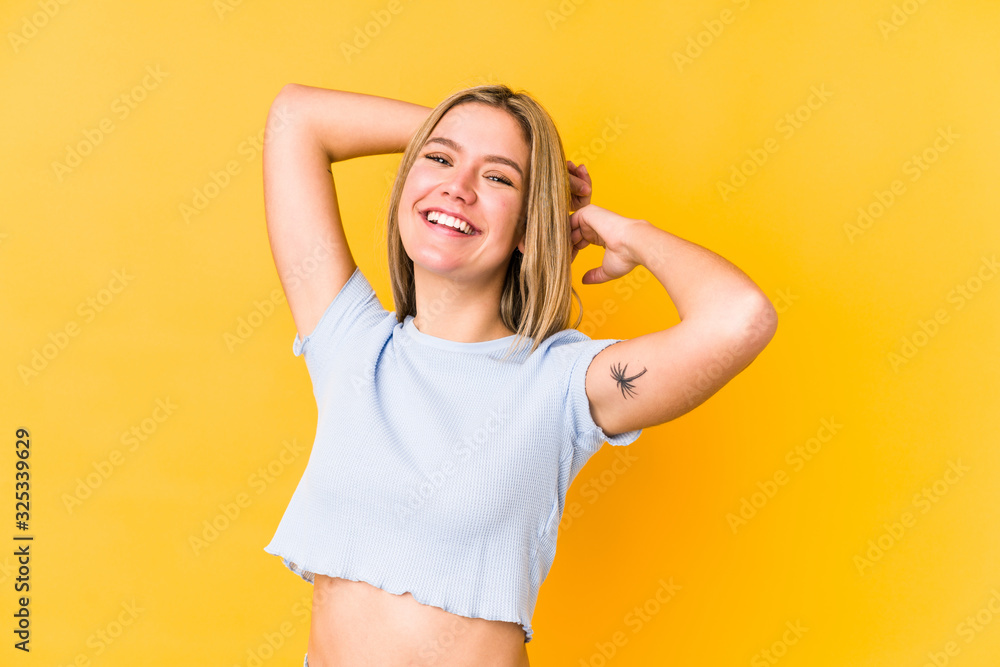 Young blonde caucasian woman isolated on yellow background stretching arms, relaxed position. Young blonde caucasian woman isolated on yellow background stretching arms, relaxed position.