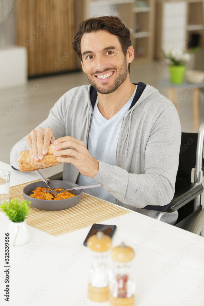 happy disabled man in wheelchair having a meal happy disabled man in wheelchair having a meal