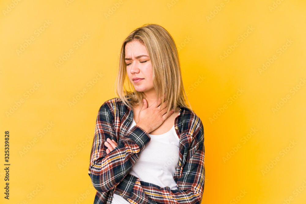 Young blonde caucasian woman isolated on yellow background suffers pain in throat due a virus or infection. Young blonde caucasian woman isolated on yellow background suffers pain in throat due a virus or infection.