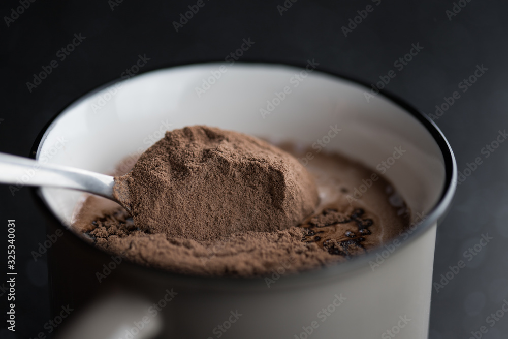A spoonful of cocoa poured into the milk close-up shot A spoonful of cocoa poured into the milk close-up shot
