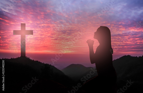 Canvas Print Silhouette of woman kneeling and praying tp god over beautiful sunrise