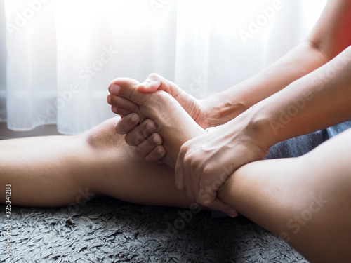Acute foot pain of thai Asian women, Using hand massage on feet to relieve severe sore feet. Medical health care concept.