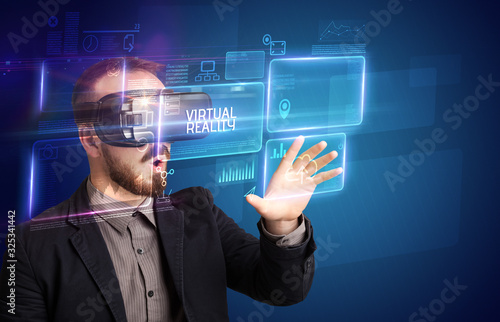 Businessman looking through Virtual Reality glasses with VIRTUAL REALITY inscription, new technology concept