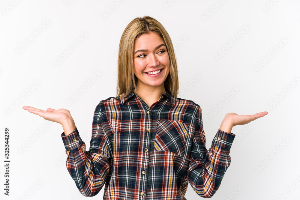 Young blonde caucasian woman isolated makes scale with arms, feels happy and confident. Young blonde caucasian woman isolated makes scale with arms, feels happy and confident.